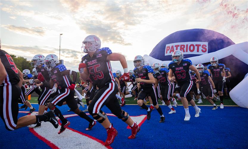 Football players run through a banner